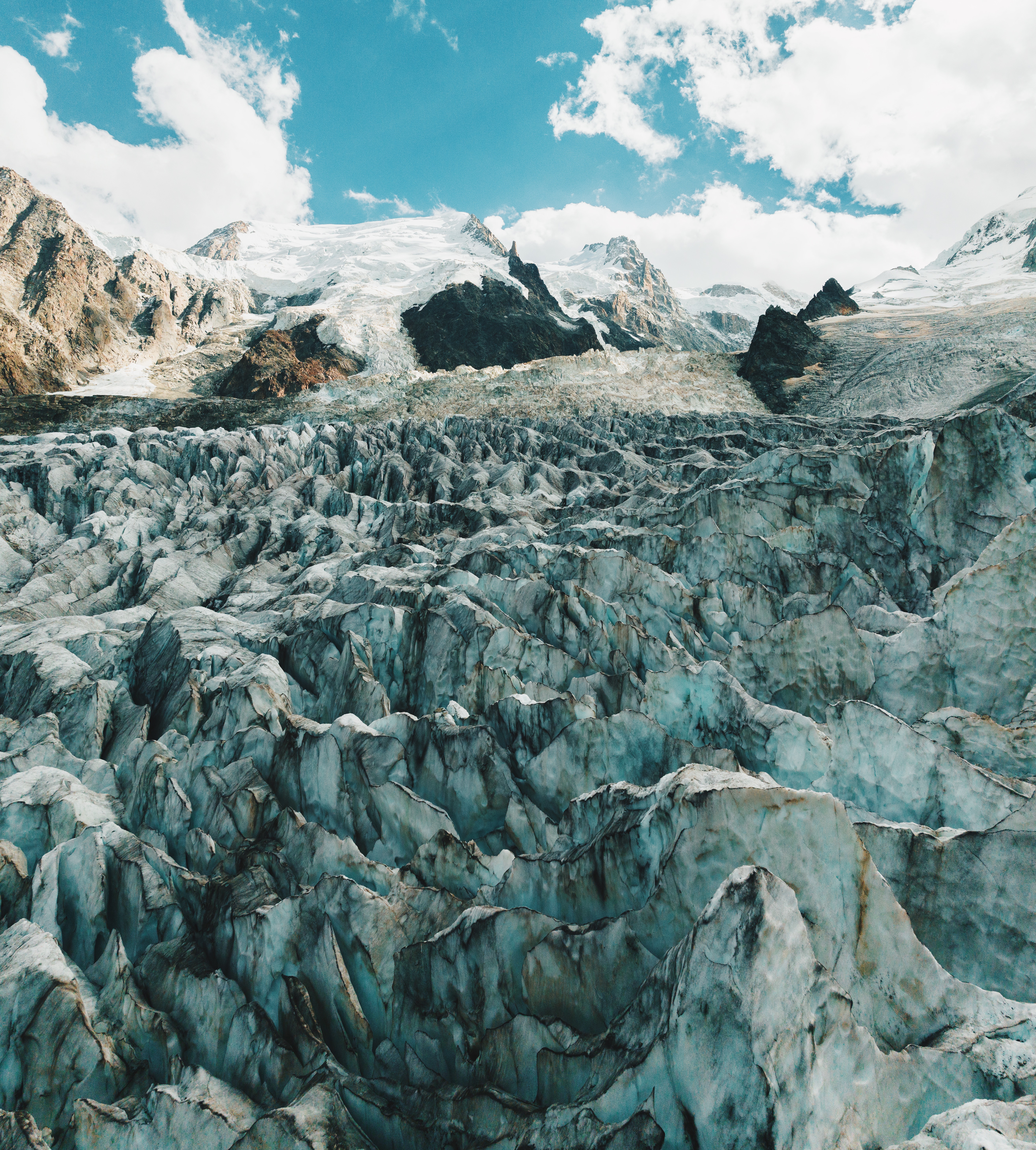 Un glacier aux crevasses bleutées, sous les sommets et un ciel turquoise